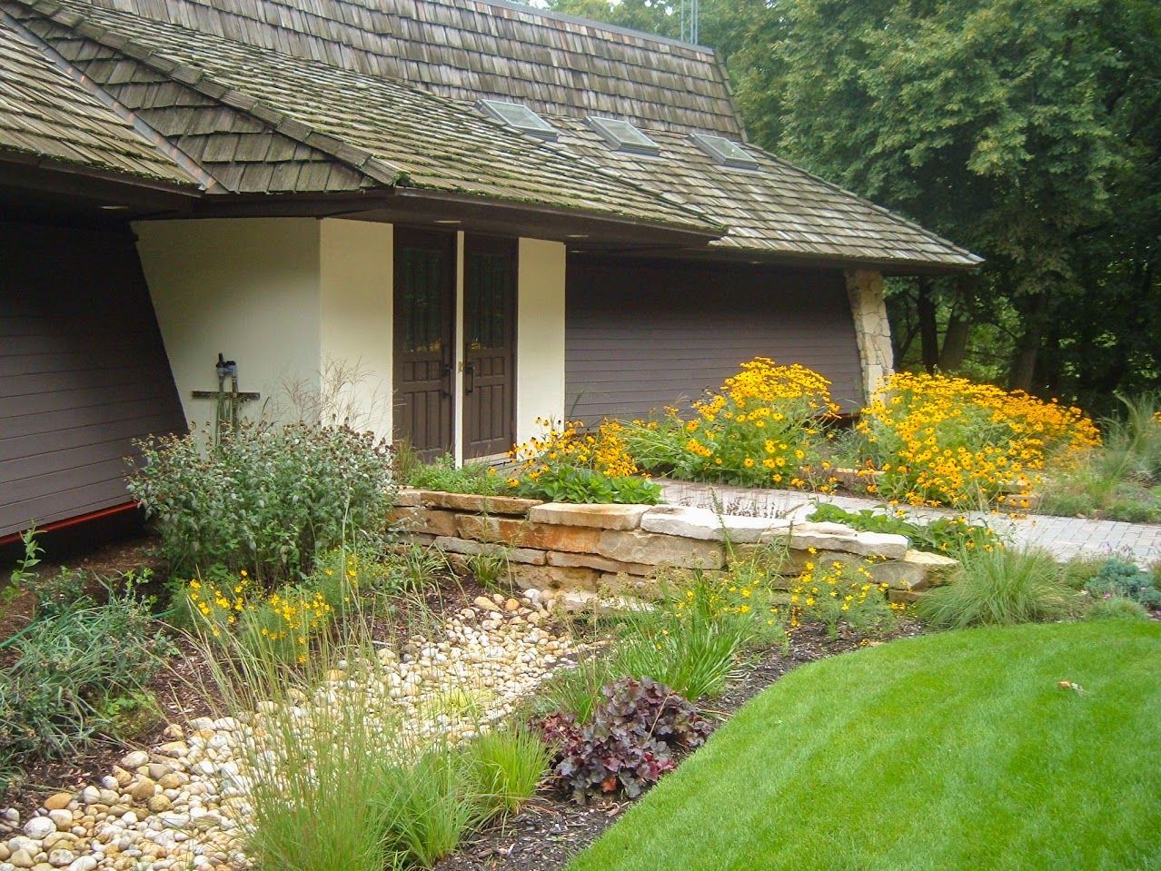 A house with a wooden roof and a garden in front of it