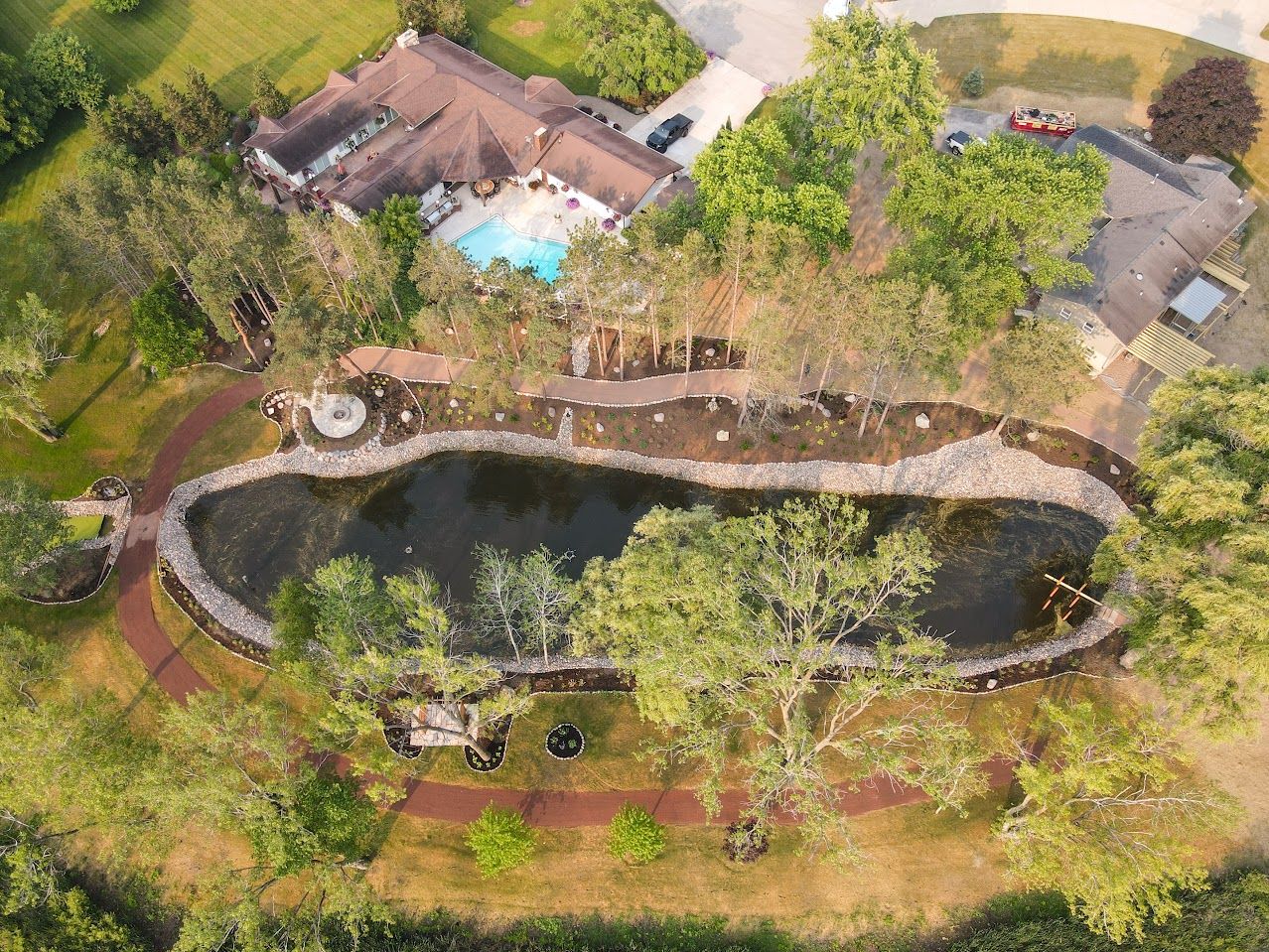 An aerial view of a large pond surrounded by trees and a house.