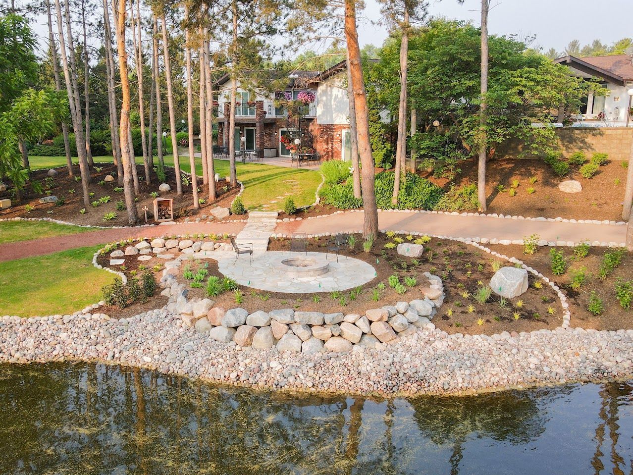 There is a fire pit in the middle of a pond surrounded by trees