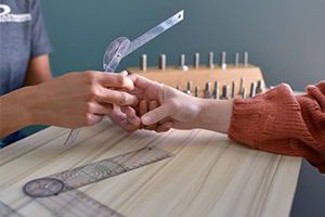 a woman is sitting at a table doing hand therapy