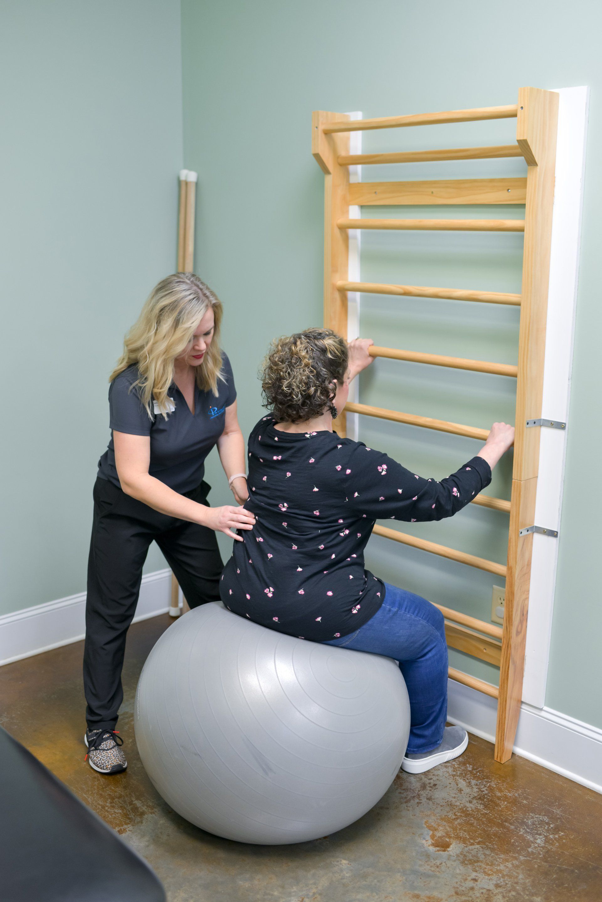 a woman is sitting on an exercise ball while a nurse helps her