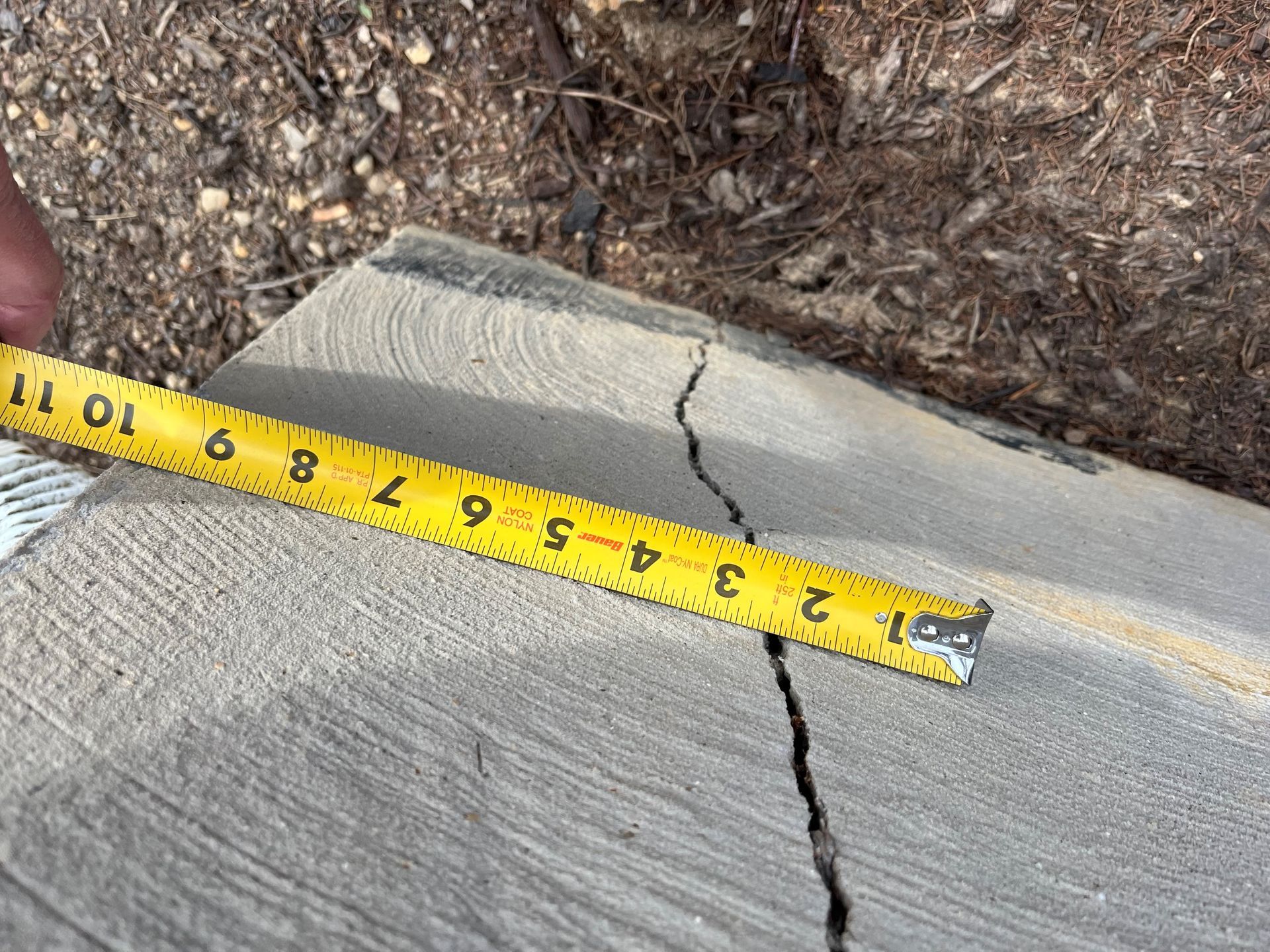 a person is measuring a crack in the concrete