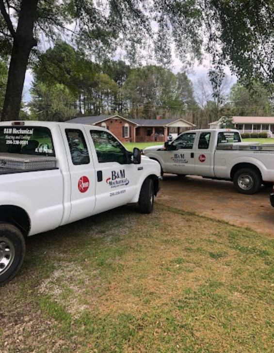 Two white trucks are parked next to each other in a grassy area.
