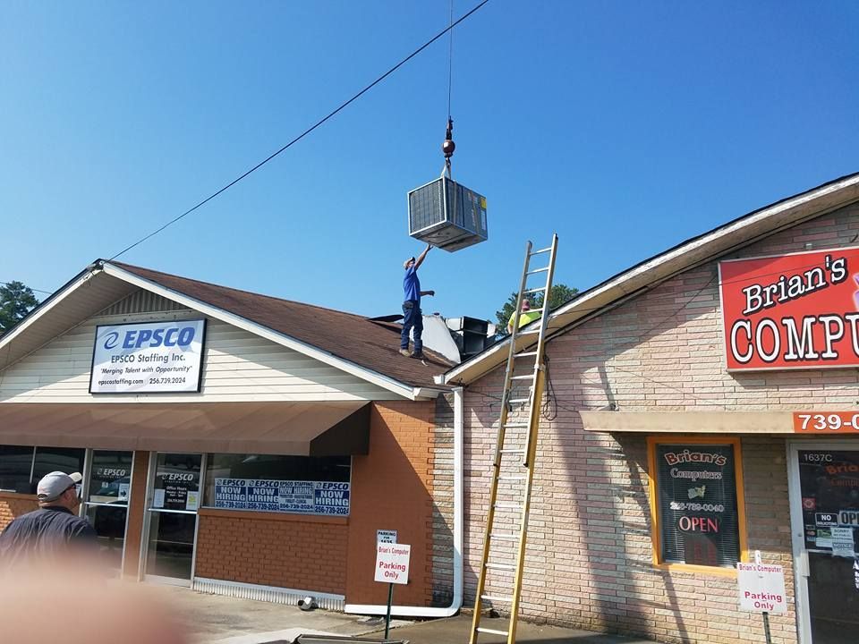 A man is standing on the roof of a building installing HVAC.
