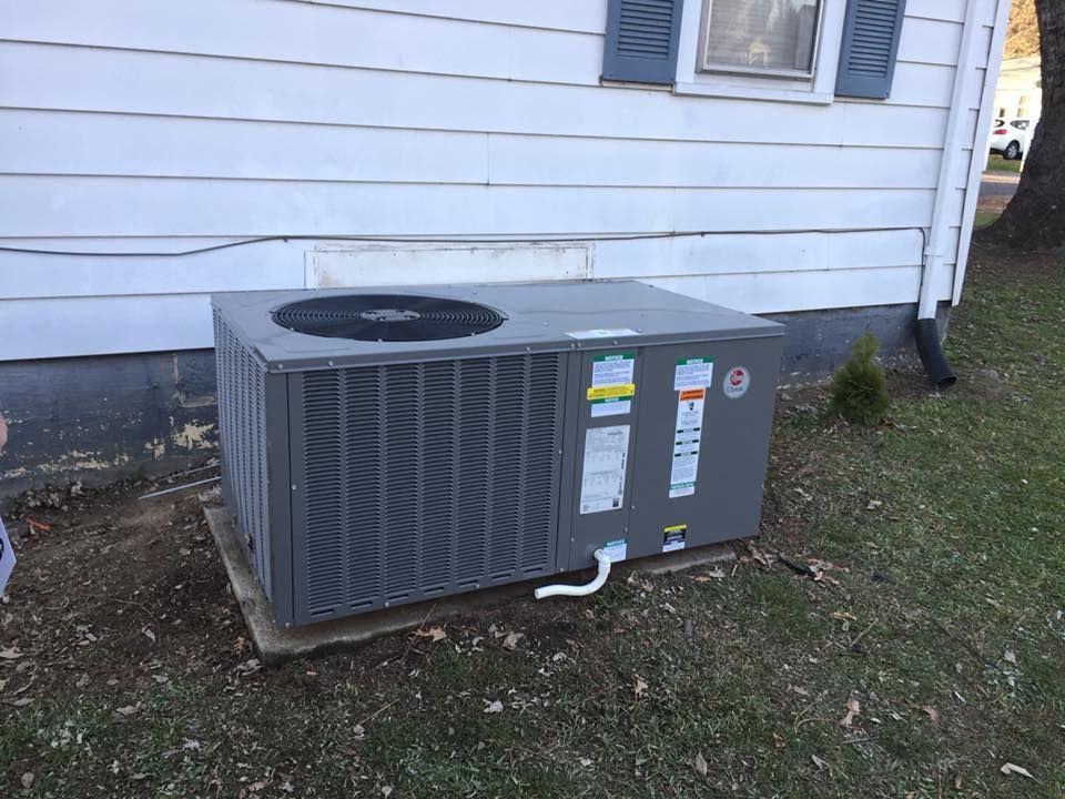 An air conditioner is sitting on the side of a house.