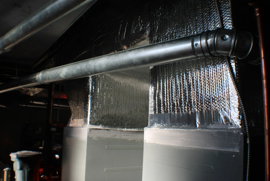 A close up of a pipe in a room with aluminum foil on it.