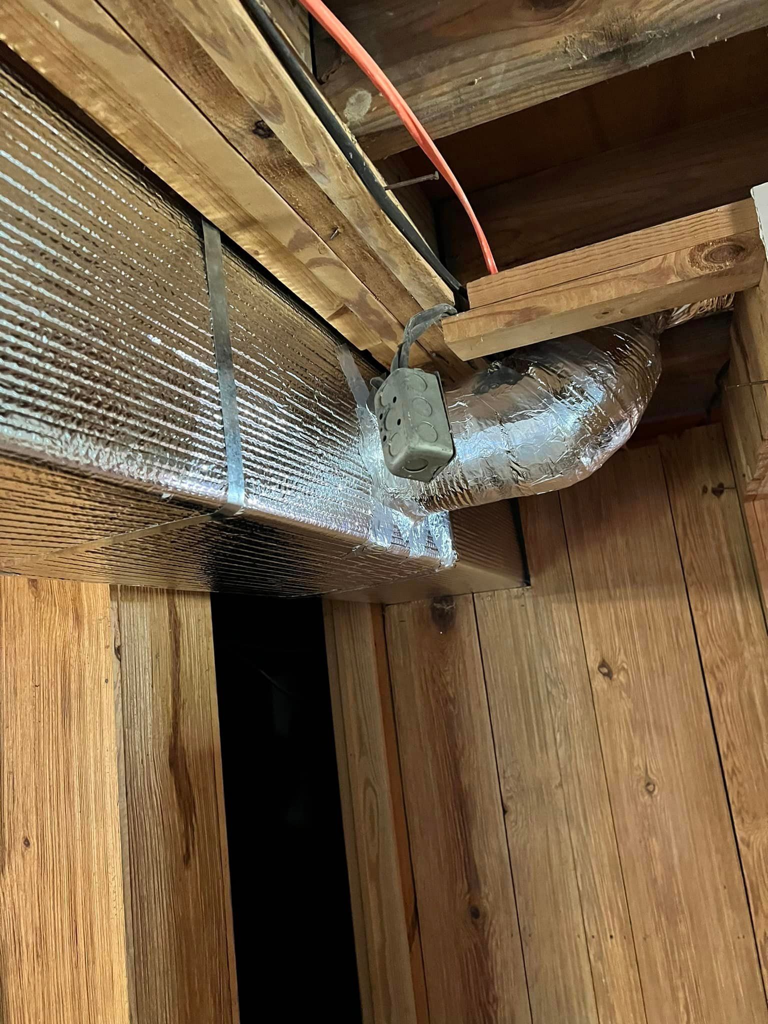 A duct is hanging from the ceiling of a wooden building.