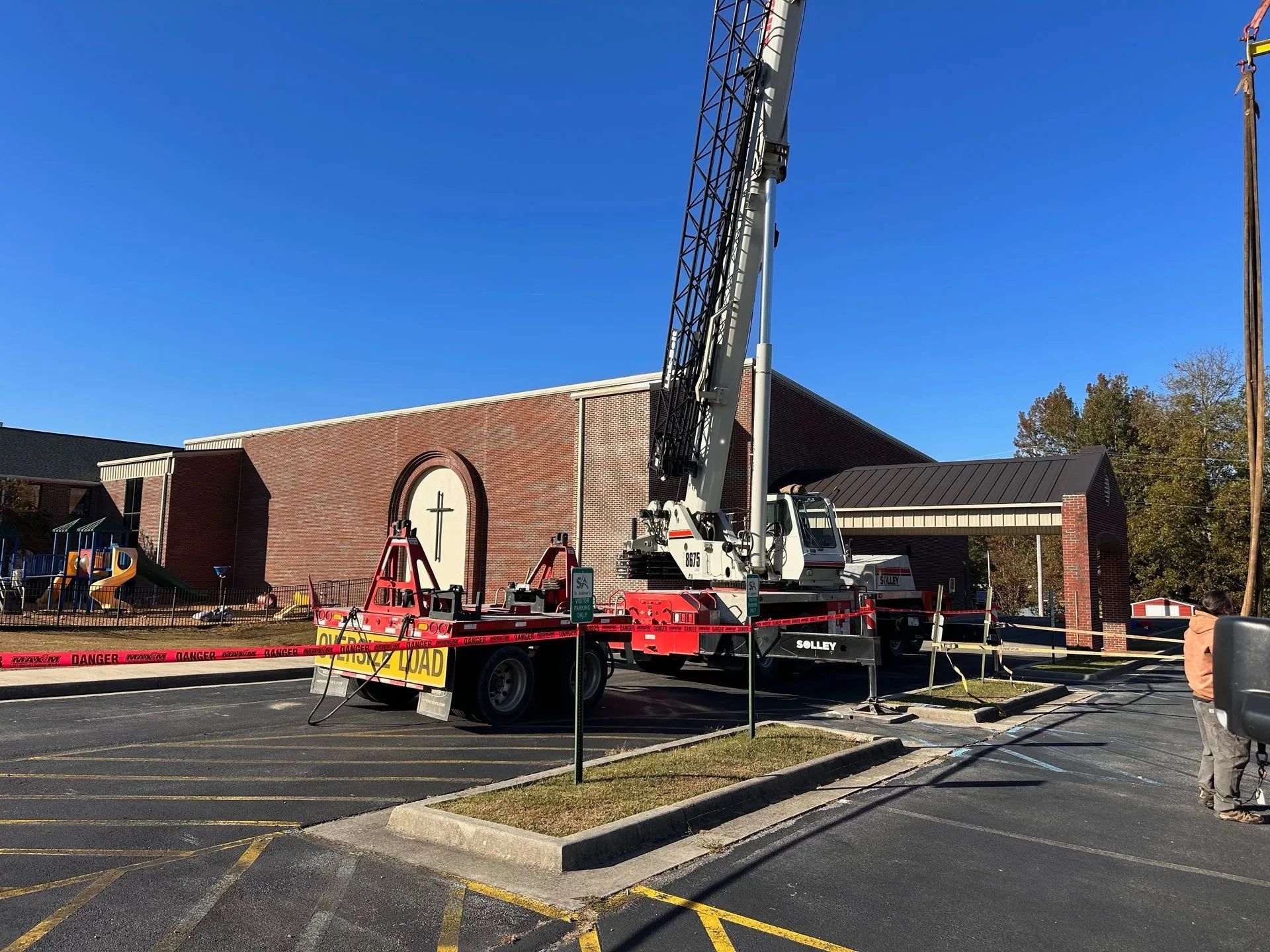 A large crane is parked in front of a brick building.