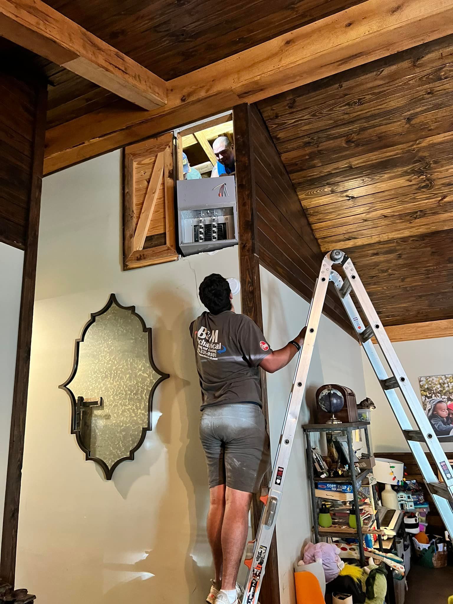 A man is standing on a ladder in a living room.
