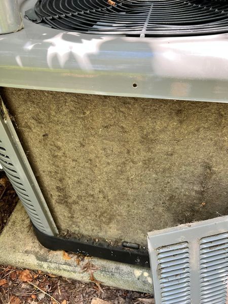 A close up of a dirty air conditioner with a fan.