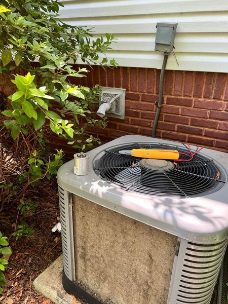 A dirty air conditioner is sitting outside of a brick house.