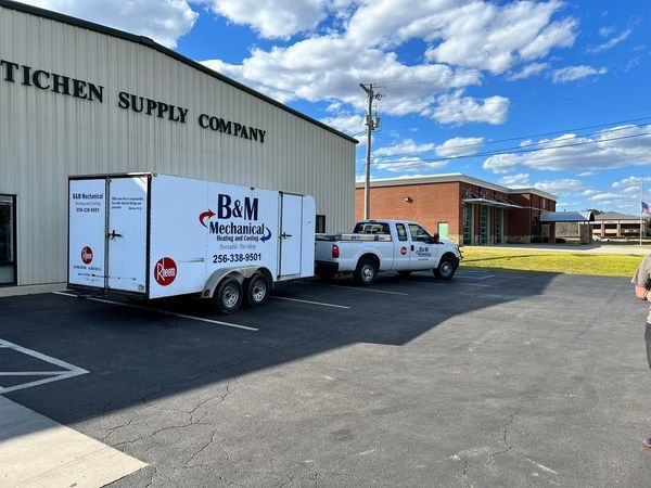 A B & M trailer is parked in front of a building.