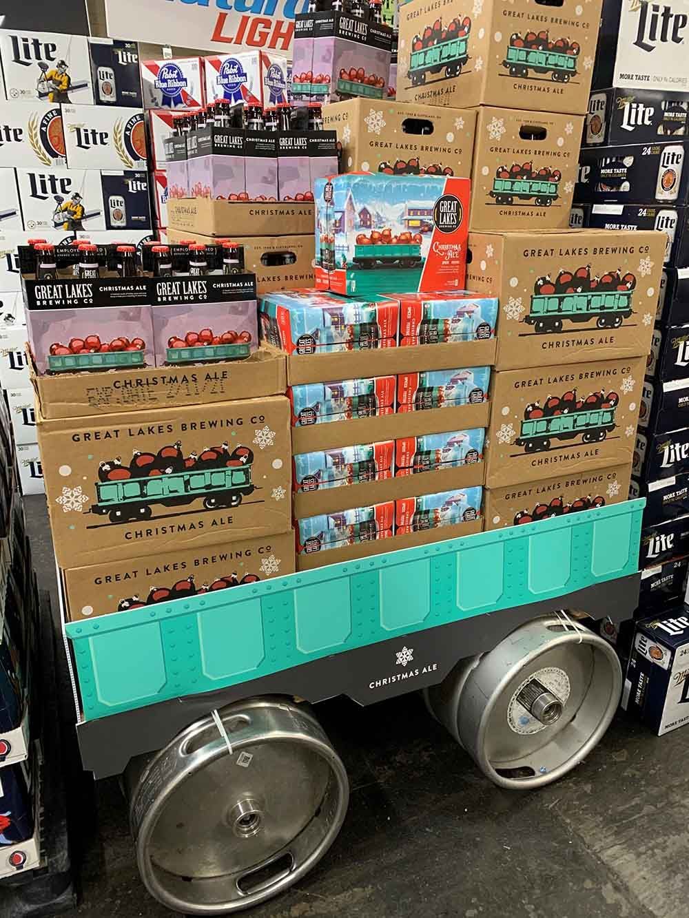 A cart filled with boxes of beer and kegs in a store.