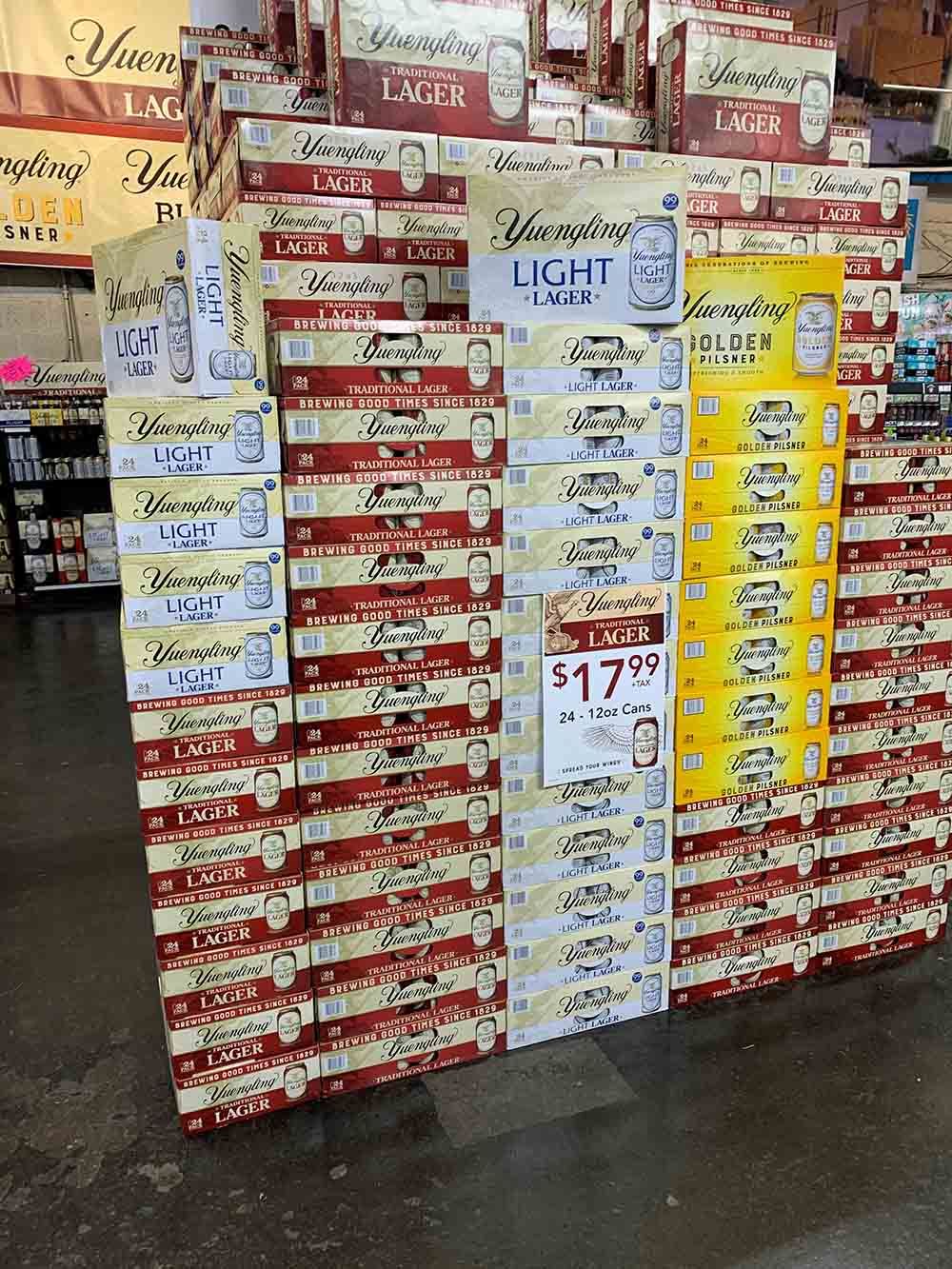 A bunch of boxes of beer are stacked on top of each other in a store.
