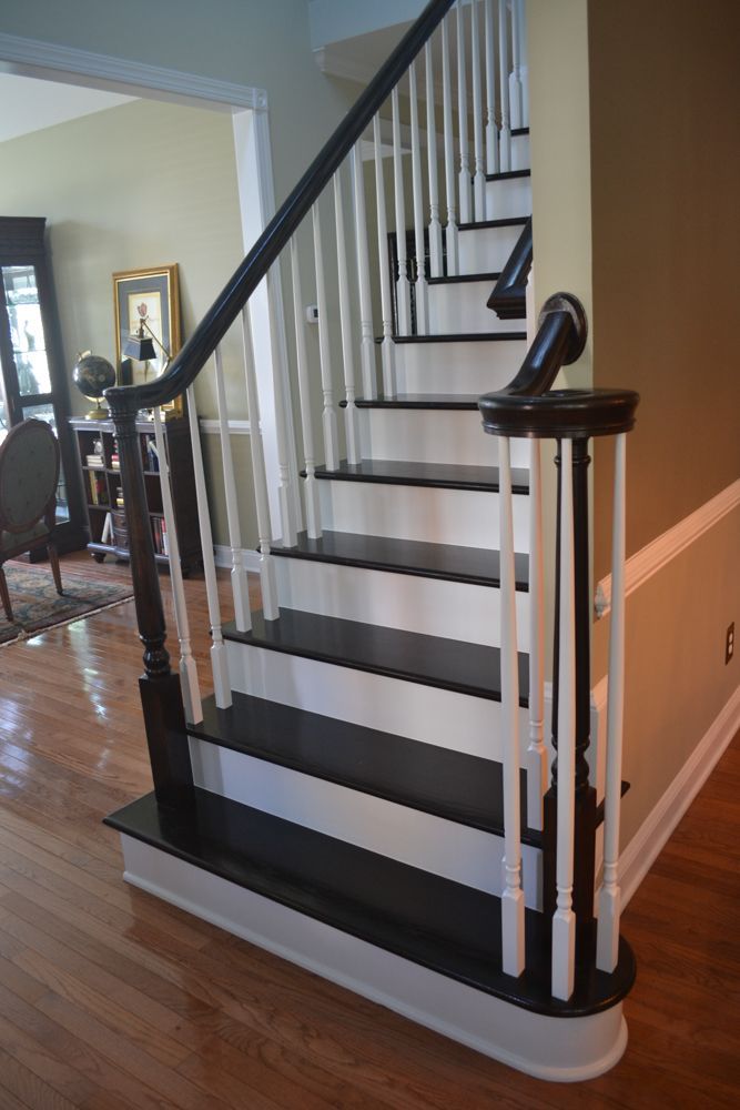 A black and white staircase with a black railing in a living room.