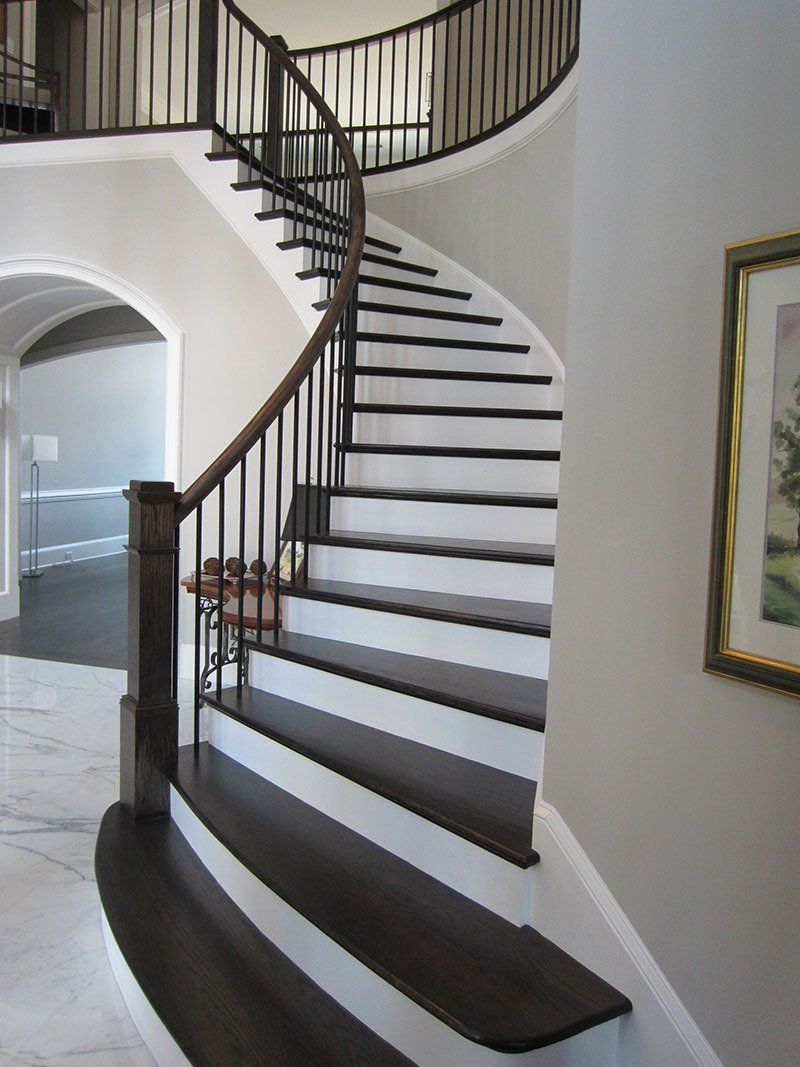 A curved staircase in a house with a picture on the wall
