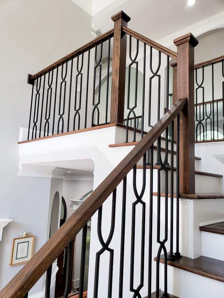 A wooden staircase with a black railing in a house.