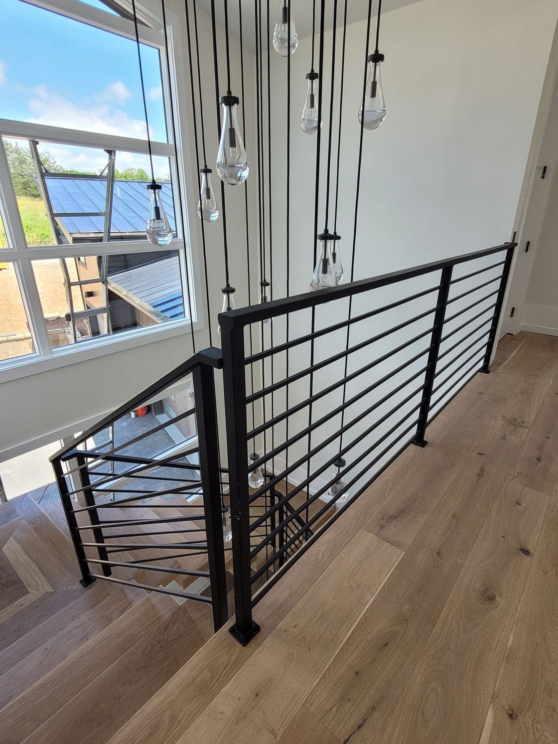 A staircase with a black railing and a large window.