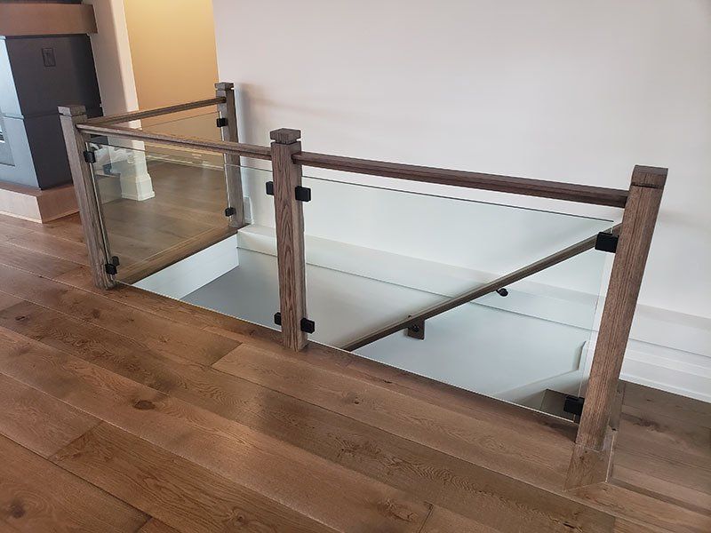 A wooden staircase with a glass railing and a wooden handrail.