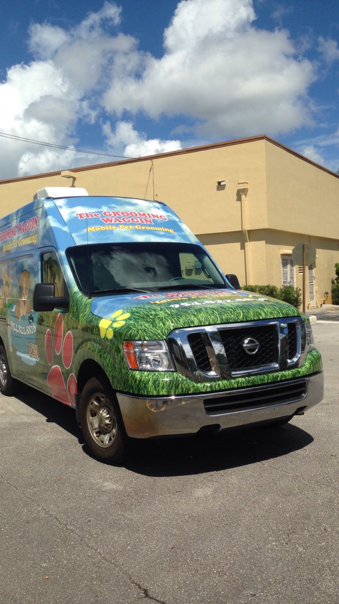 A green and blue van is parked in front of a building.