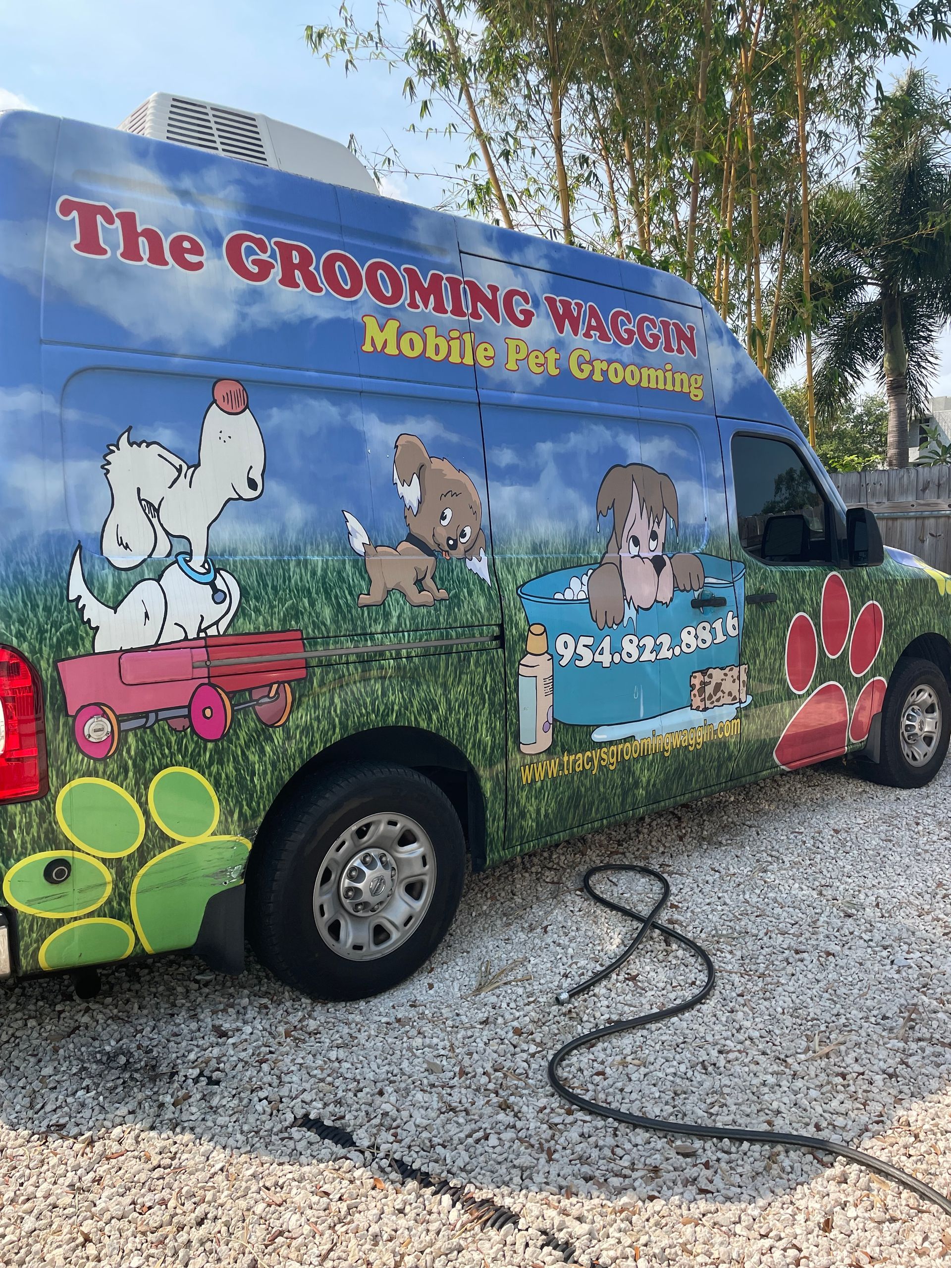 The grooming monster mobile dog grooming van is parked on gravel.