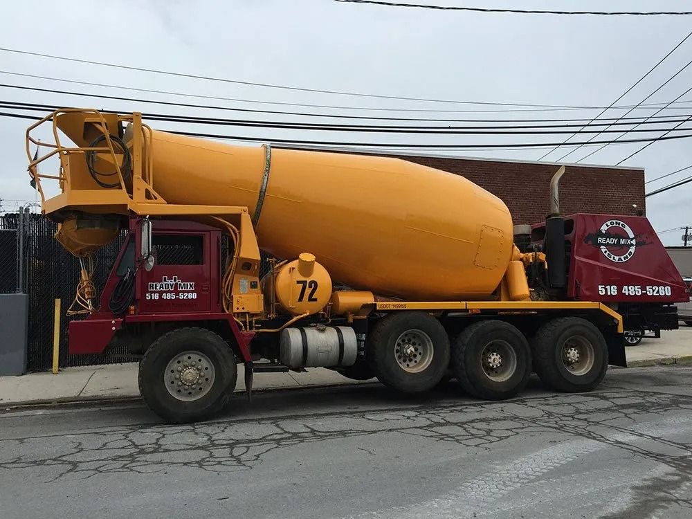Yellow and maroon concrete mixer truck parked on a street.