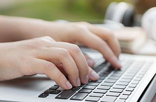 A person is typing on a laptop keyboard.