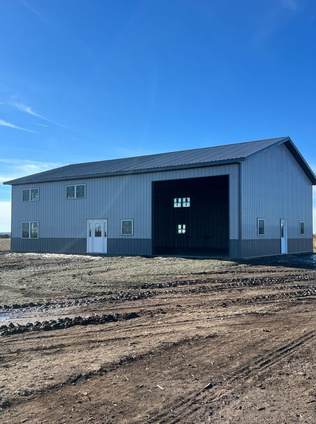 A large building is sitting in the middle of a dirt field.