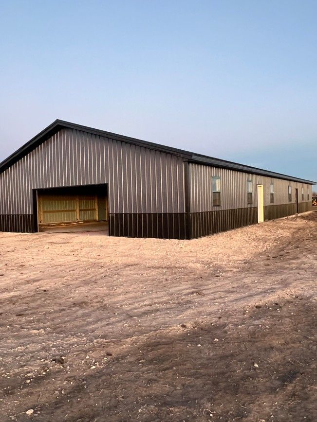 A large building with a lot of windows is sitting in the middle of a dirt field.