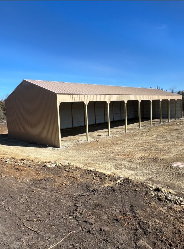 A large building with a lot of doors is sitting in the middle of a dirt field.