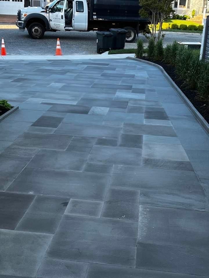 Gray stone paver driveway with truck in background.