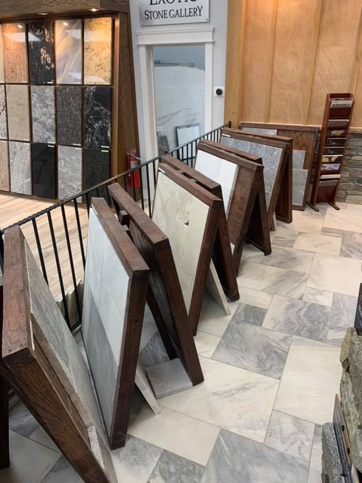 Interior of a stone gallery with various tile samples displayed on wooden easels, and a display of stone tiles on a wall.