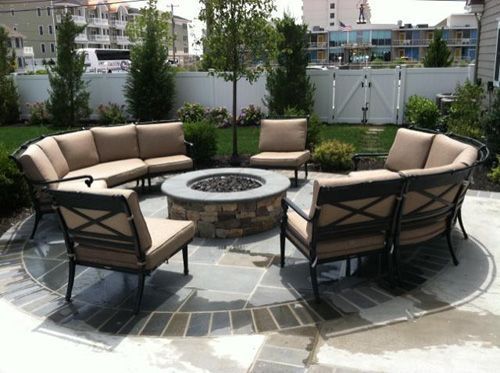 Outdoor seating area with a circular fire pit and sectional sofa.