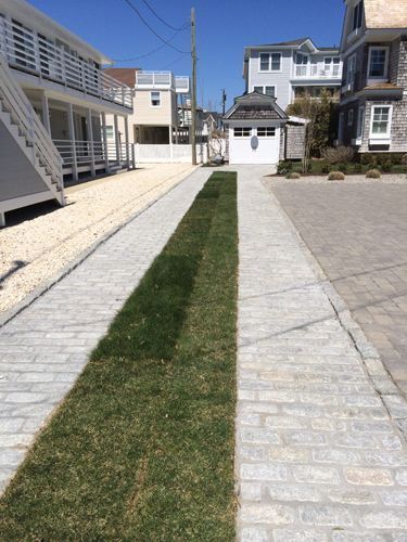 Driveway with grass strip, brick pavers, and beach homes.