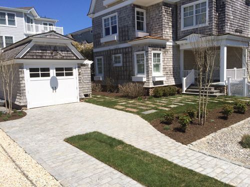 House with gray shingle siding, white trim, and a brick driveway. Garage on the left.