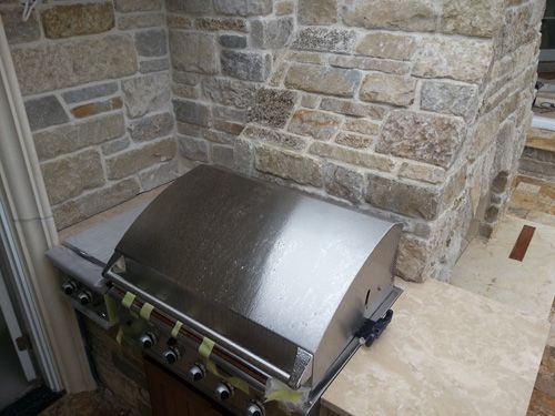 Stainless steel grill built into stone wall.