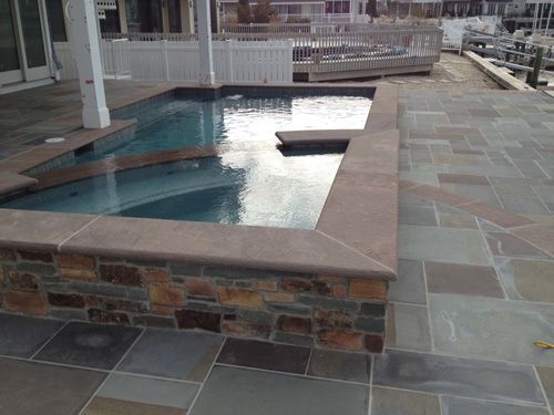 Small swimming pool with stone surround and patio.
