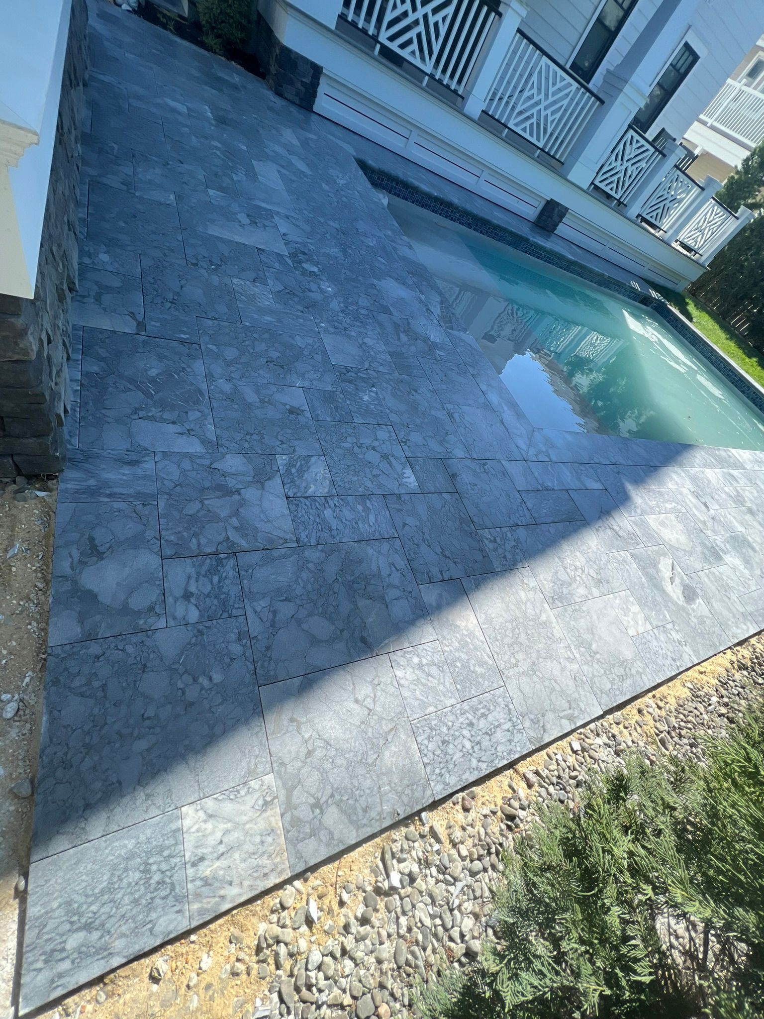Stone patio with a pool next to a building.