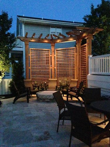 Patio with pergola and seating around a fire pit at dusk.