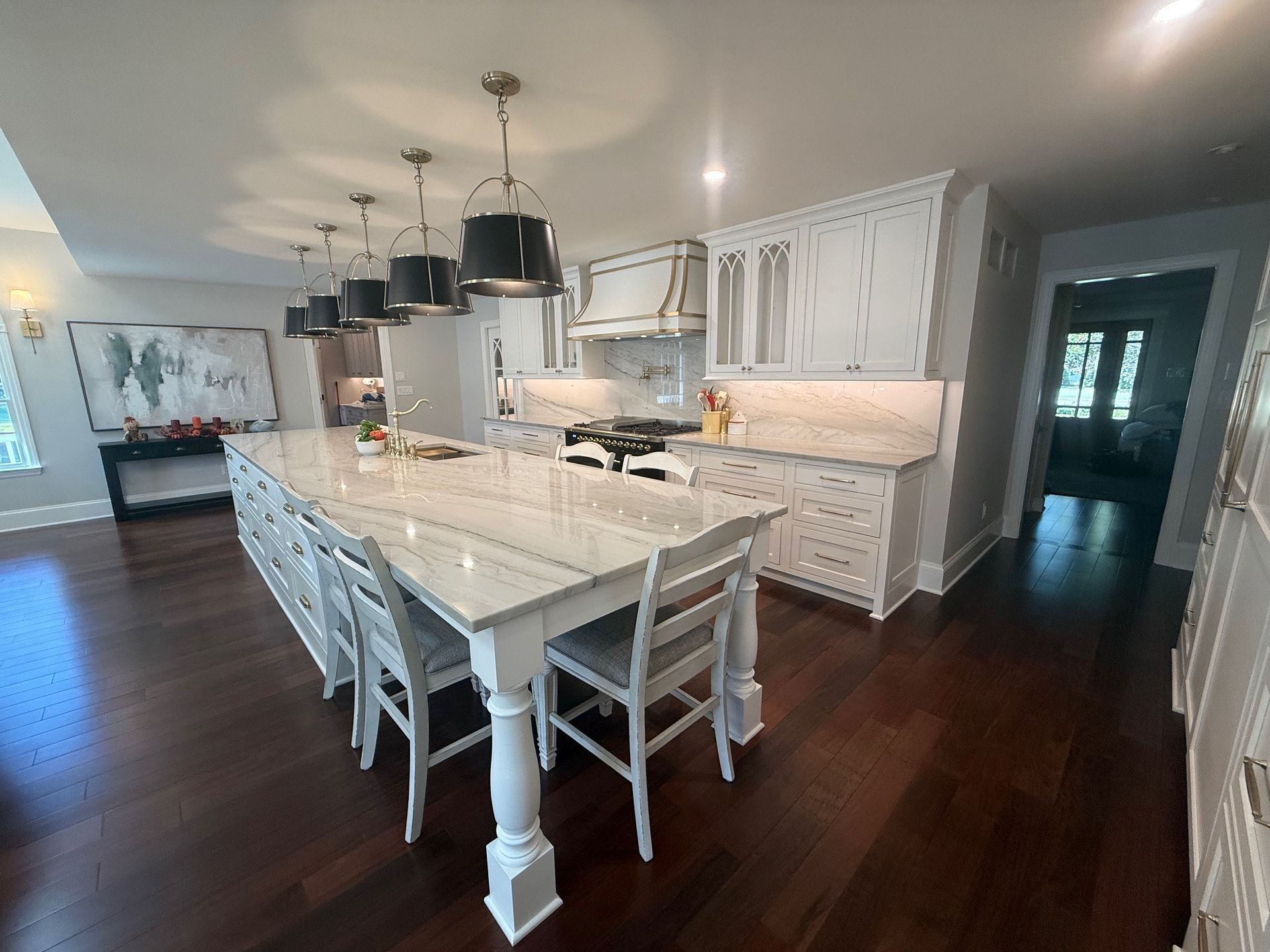 Spacious white kitchen with dark wood floors and large island with seating.