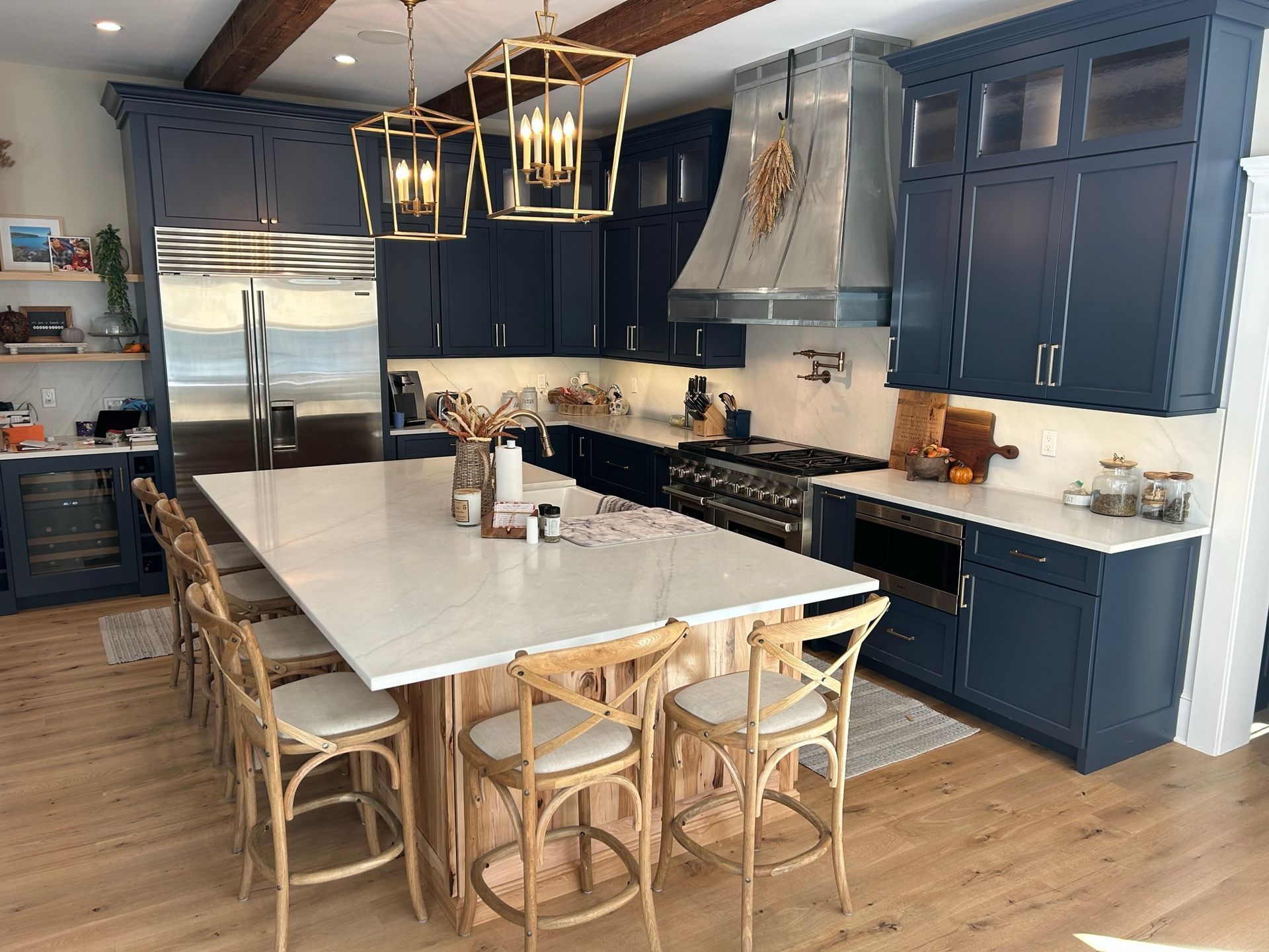 Blue kitchen with island, stainless steel appliances, and wooden beams.