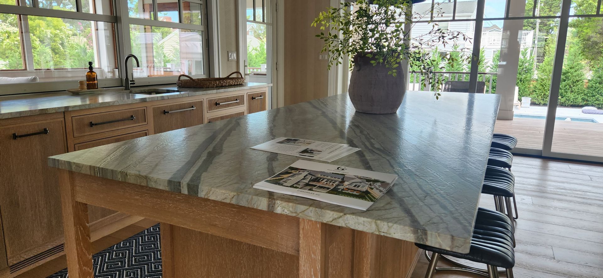 Kitchen with marble countertops, wooden cabinets, and a potted plant on the island.