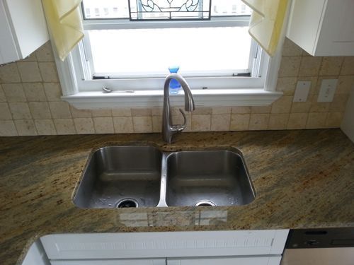 Kitchen sink with granite countertop and window.