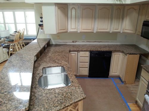 Kitchen with granite countertops, stainless steel sink, light cabinets, and black dishwasher.