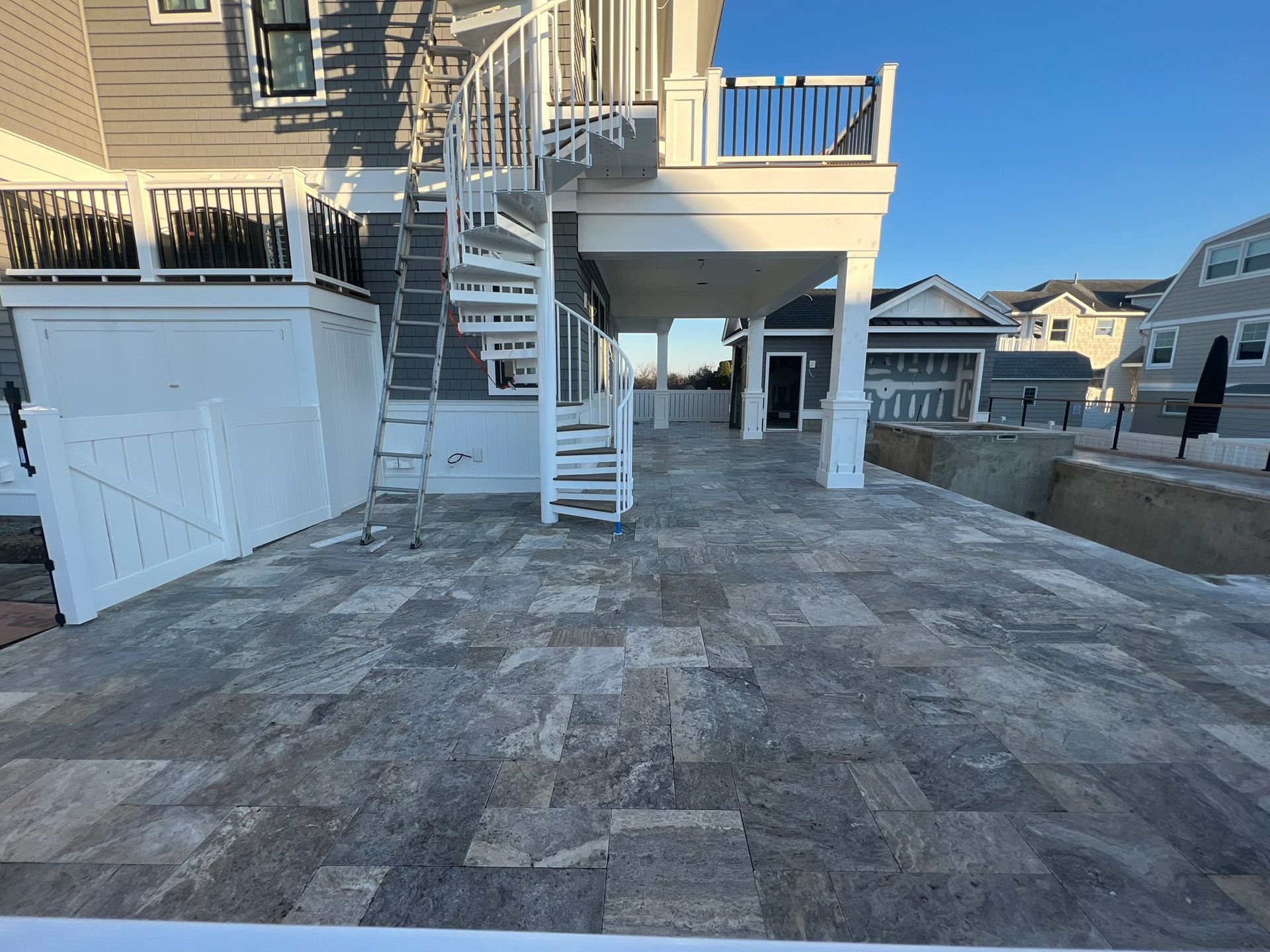 Stone patio with a spiral staircase leading to a covered deck on a multi-story building.