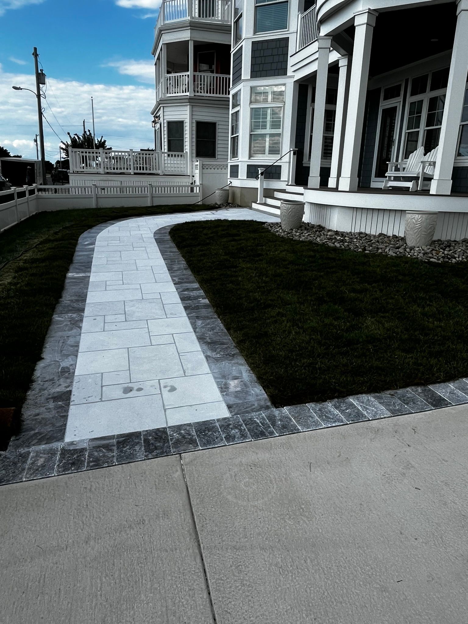 Paved walkway leading to a multi-story building with a manicured lawn on a sunny day.