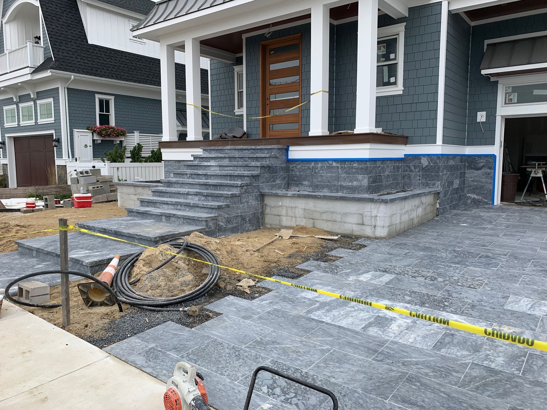 House under construction, with gray brick steps and walkway. Yellow caution tape in foreground.