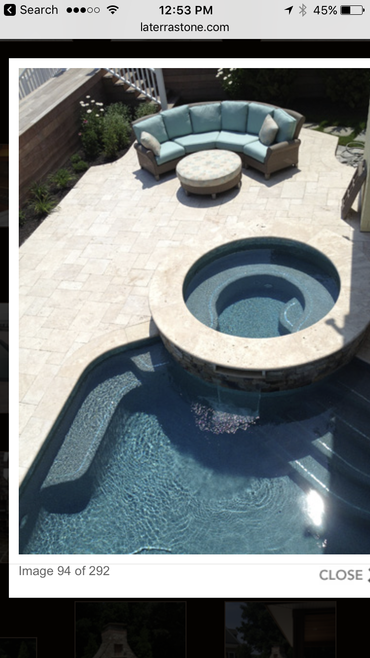 Overhead view of a pool area with a round spa and sectional seating on a stone patio.