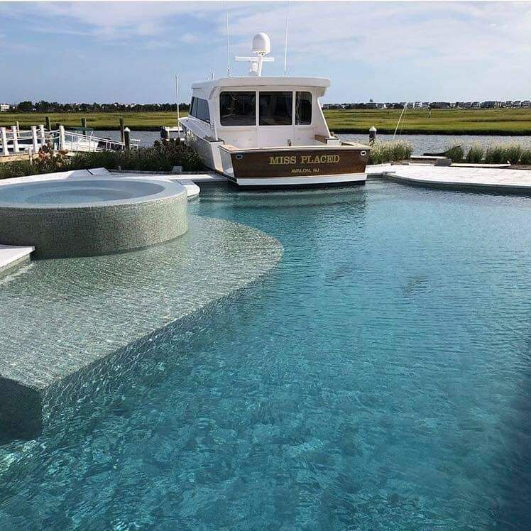 Swimming pool with boat docked behind it; white boat named 