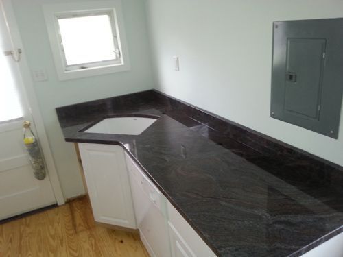 A countertop with a sink and cabinets against a light wall, next to a door.